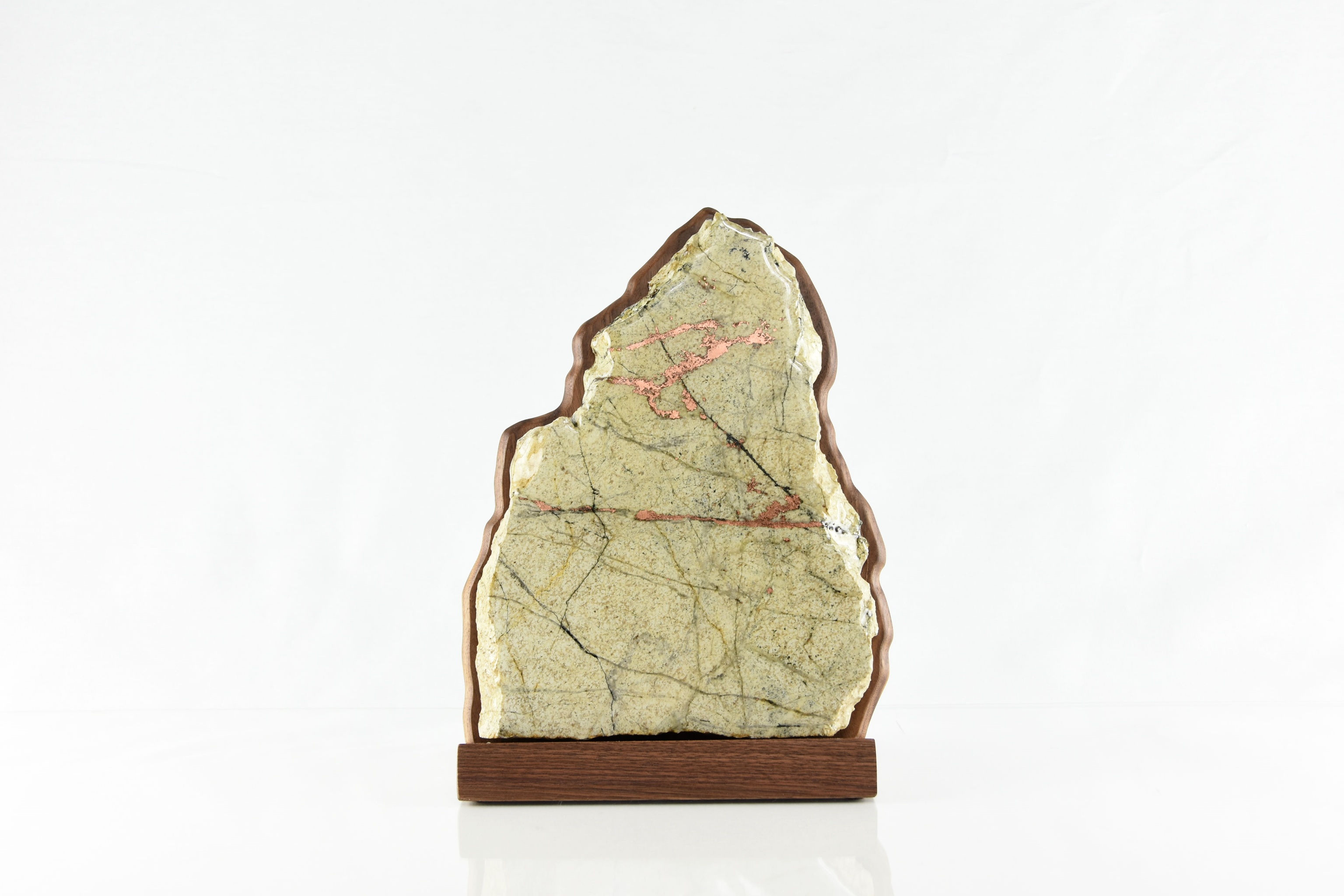 Fossil Monolith — a sculpted stone slab held in a walnut cradle on a walnut base